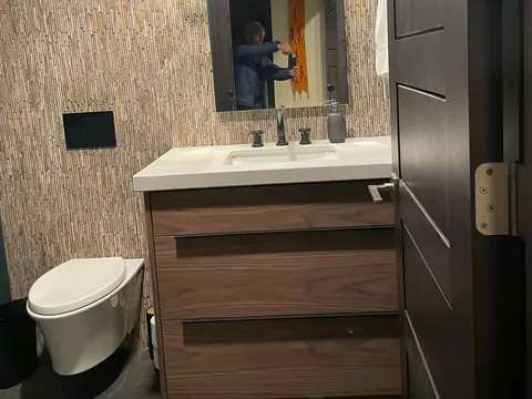 Wood vanity and toilet beside a glass shower
