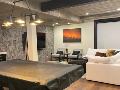 Lower-level lounge with dark coffee table, sectional seating, and wood ceiling