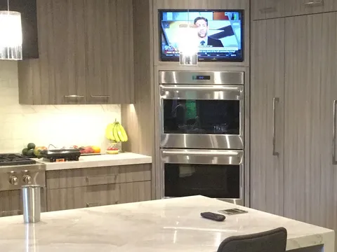 Corner kitchen nook with built-in double ovens and a TV