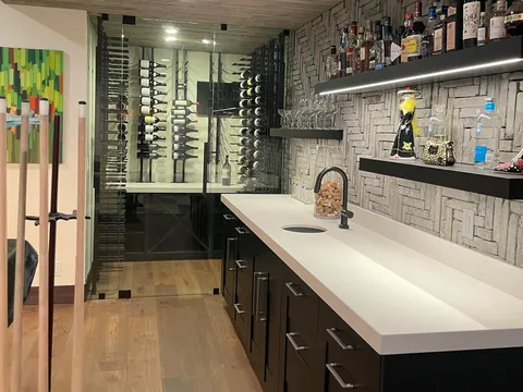 Bar with bottle shelves, a long counter, and glass-front storage