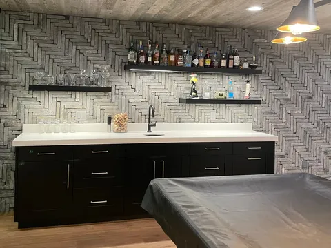 Dark-cabinet wet bar with a pale countertop and wood ceiling