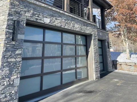 Multi-level home exterior with stone cladding and garage doors