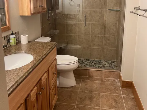 Bathroom with glass shower, wood vanity, and tiled floor