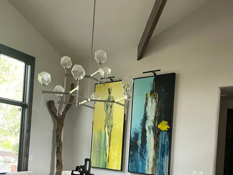 Dining table with white chairs beneath large colorful wall art