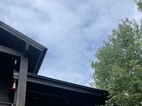 Dark-sided multi-story home exterior with stone lower level and balcony