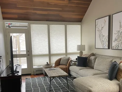 Lounge with gray sectional, wood ceiling, and hardwood floor