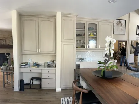 Dining area with a long wood table, white built-in cabinetry, and a kitchen beyond