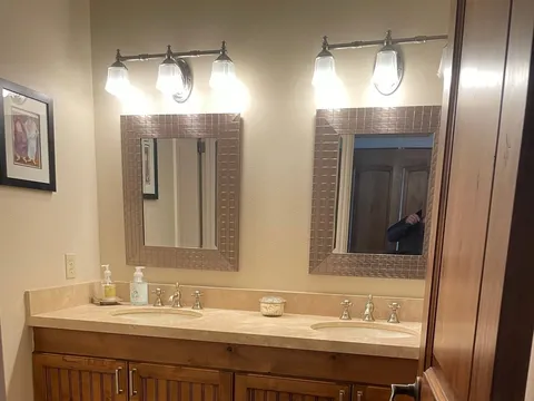 Double-sink wood vanity with two framed mirrors and tile floor