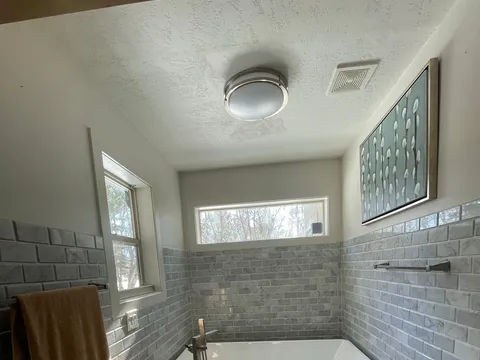 Compact bathroom with tiled tub and shower, toilet, and a wood vanity